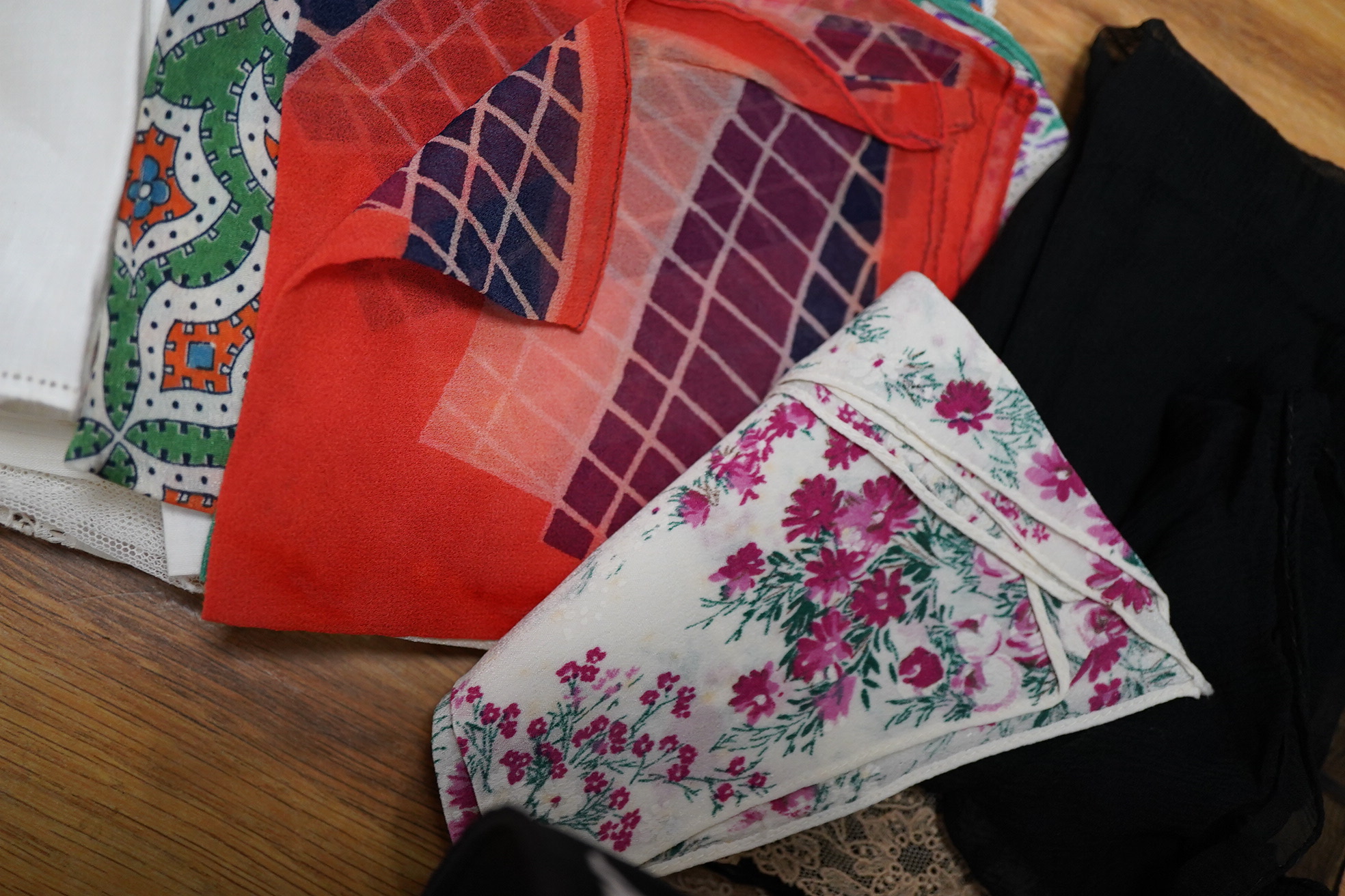 A collection of hankies, including a silk circa 1985 Christian Dior silk advertising ‘Poison’ hanky, Honiton bobbin lace and four other bobbin lace hankies, mixed machine lace hankies and 1930’s printed hankies. 33cm squ
